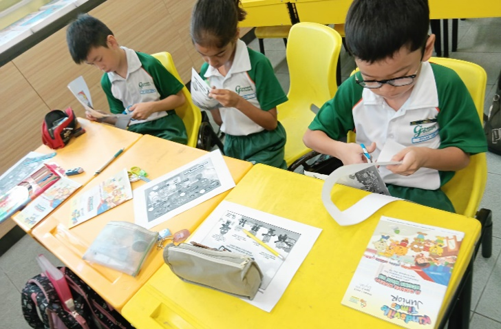 Students cutting activity sheets during a classroom learning lesson.